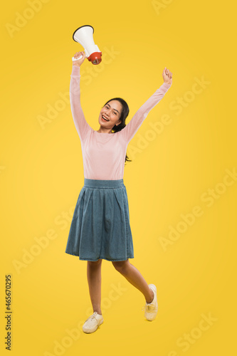 beautiful girl standing holding a megaphone while raising both hands up