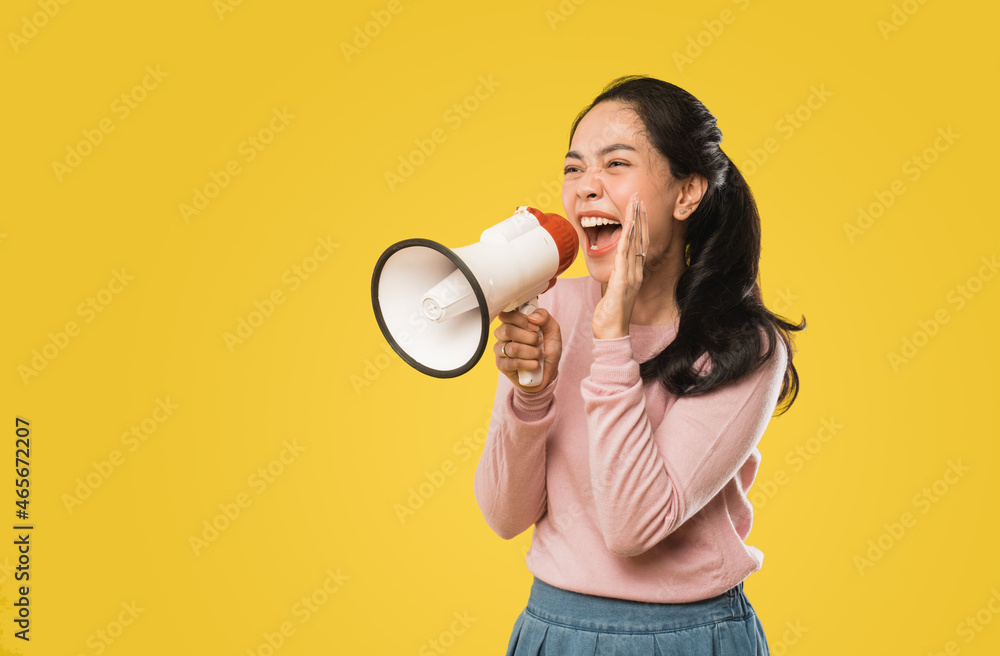 Asian woman screaming while holding megaphone with two hands making announcement Asian woman screaming while holding megaphone with two hands making announcement