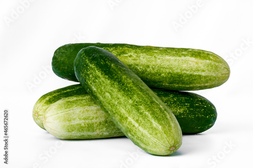 Four cucumbers for greens, in a stack composition, isolated on a white background