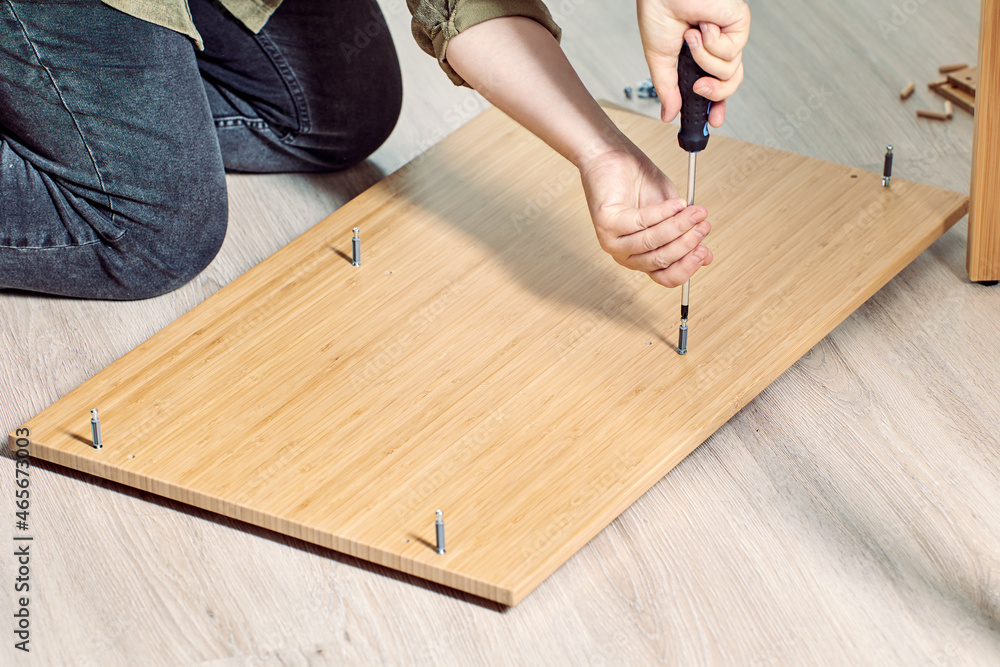 Handyman is assembling flat pack furniture with help of screwdriver. Handyman is assembling flat pack furniture with help of screwdriver.
