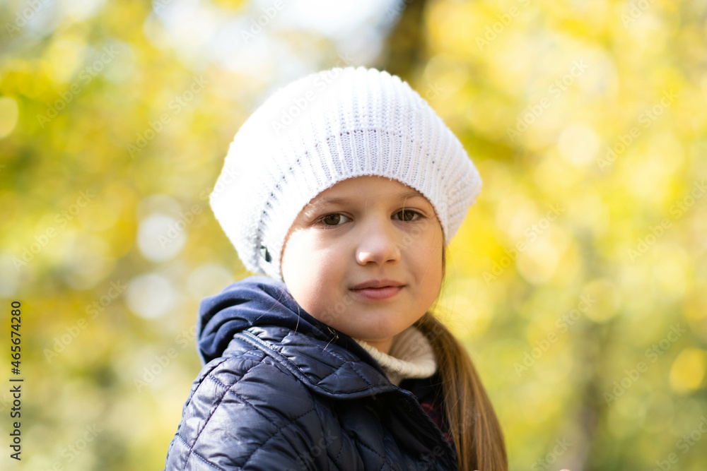Autumn portrait of cute little blond girl in white hat. Beautiful smiling child having fun outdoors on a warm fall day in city park. Happy childhood. Autumn kids fashion. Close up. Autumn portrait of cute little blond girl in white hat. Beautiful smiling child having fun outdoors on a warm fall day in city park. Happy childhood. Autumn kids fashion. Close up.