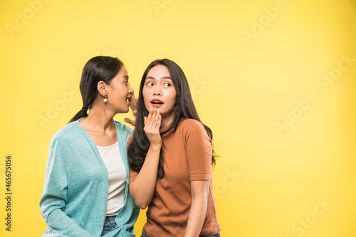 woman surprised when her friend talks whispering in her ear with copyspace