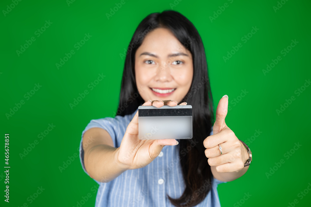 asian woman looking at camera while holding atm card with thumbs up asian woman looking at camera while holding atm card with thumbs up