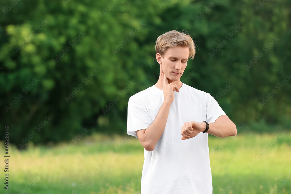 Sporty male runner checking pulse outdoors Sporty male runner checking pulse outdoors