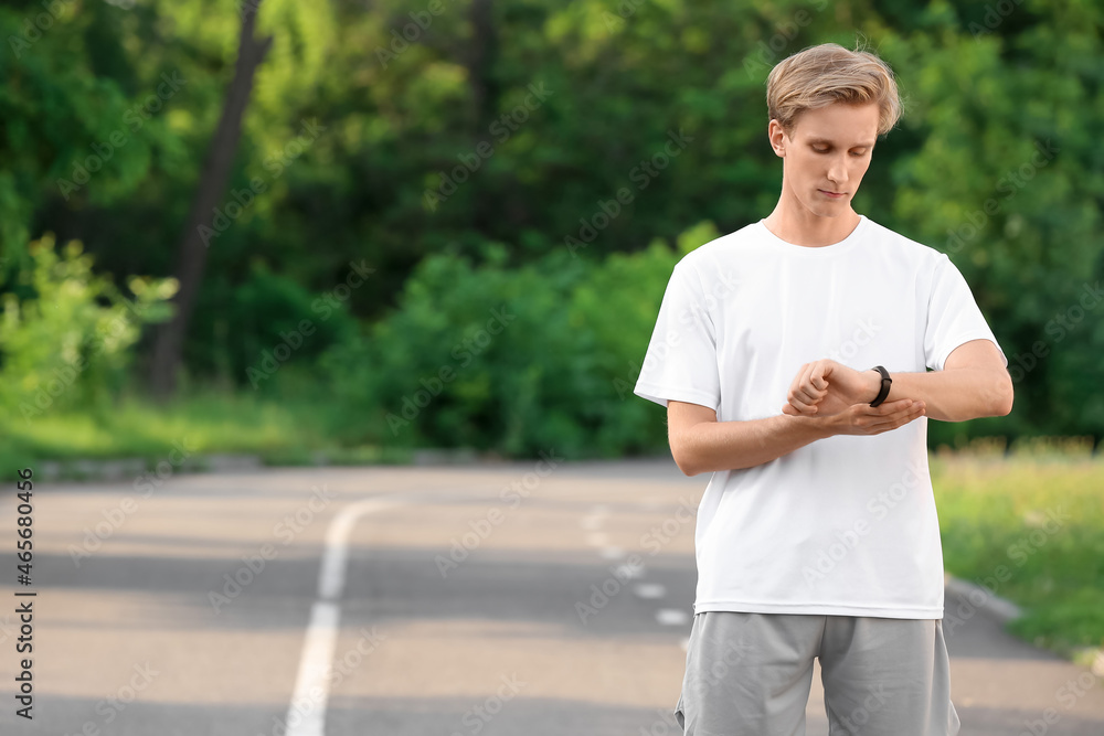 Sporty male runner checking pulse outdoors Sporty male runner checking pulse outdoors