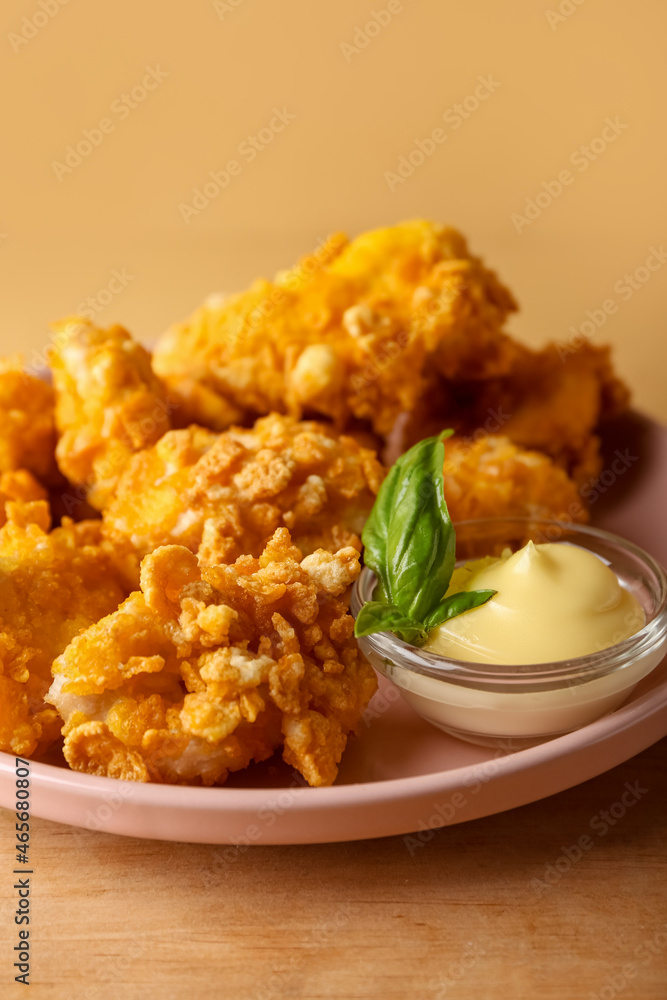 Plate with popcorn chicken, sauce and basil on color background, closeup Plate with popcorn chicken, sauce and basil on color background, closeup