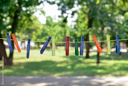 Many different clothespins hanging on laundry line outdoors