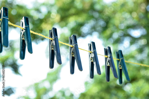 Plastic clothespins hanging on laundry line outdoors, closeup