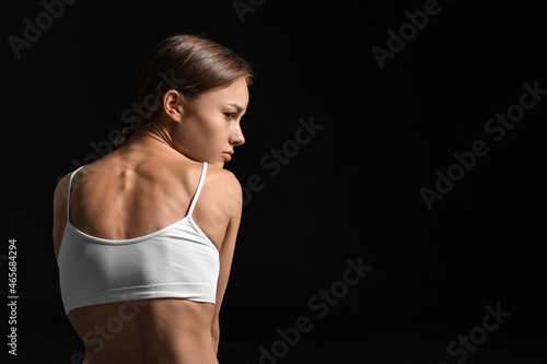Young skinny woman on dark ...