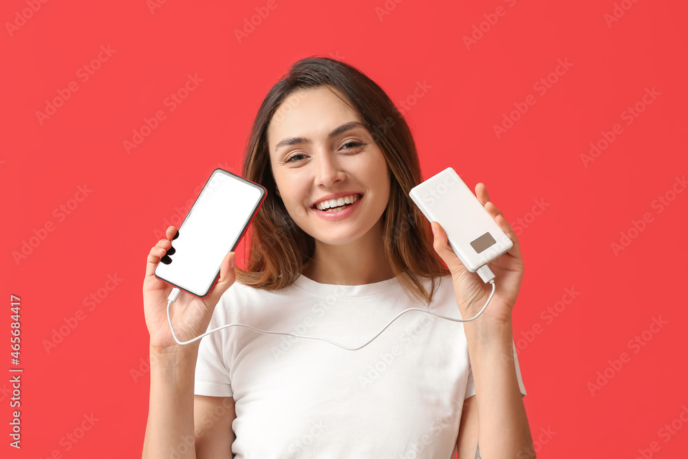 Young woman with phone and power bank on color background Young woman with phone and power bank on color background