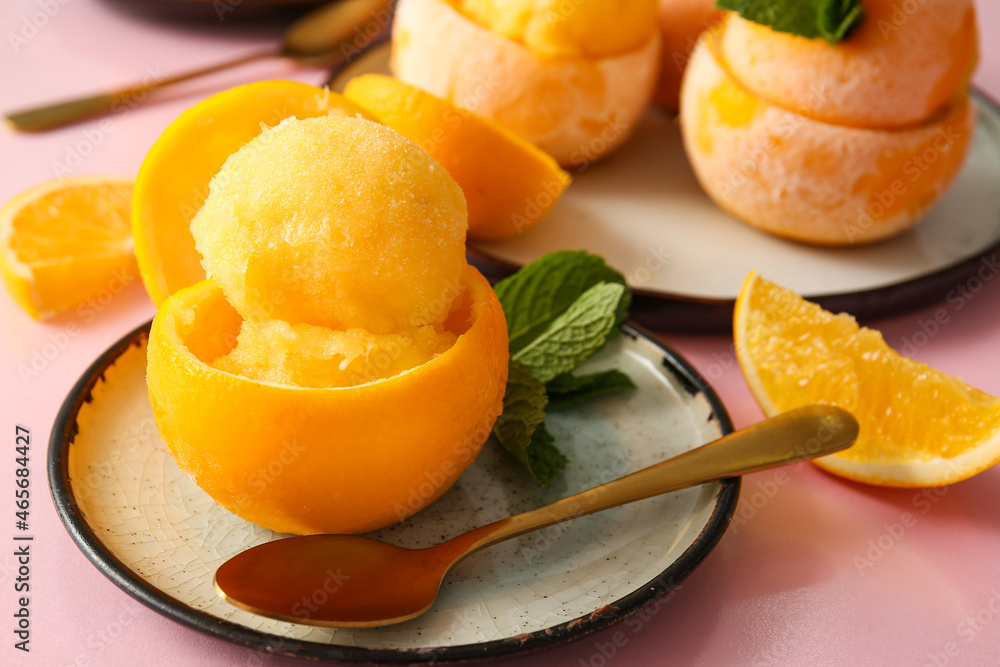 Plates with tasty ice creams in orange peels on color background Plates with tasty ice creams in orange peels on color background