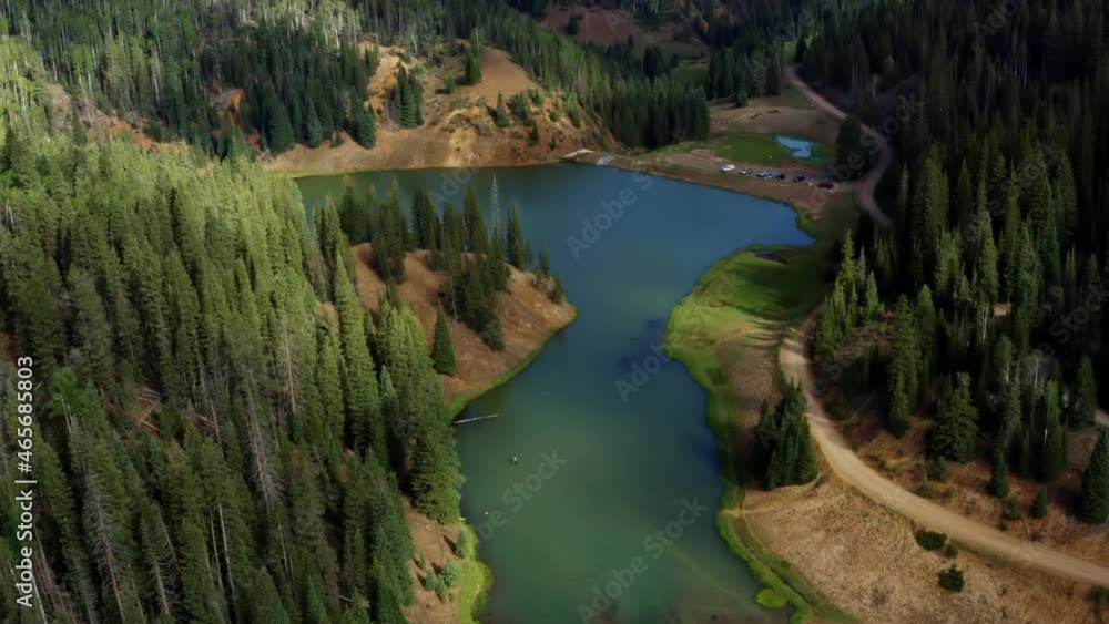 Beautiful tilting down aerial drone shot of a stunning nature landscape of the Anderson Meadow Reservoir lake up Beaver Canyon in Utah with large pine tree forest and a parking lot for fisherman Beautiful tilting down aerial drone shot of a stunning nature landscape of the Anderson Meadow Reservoir lake up Beaver Canyon in Utah with large pine tree forest and a parking lot for fisherman