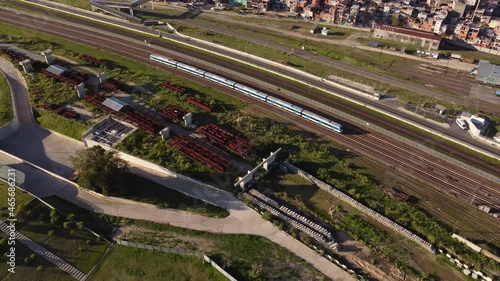 Aerial top down view of commuter train running on track and approaching railway complex. photo