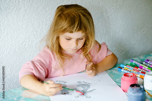 Little creative toddler girl painting with finger colors koala bear. Active child having fun with drawing animals at home, in kindergaten or preschool. Education and distance learning for children photo