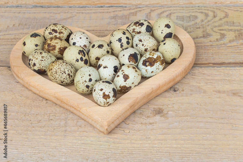 Quail eggs in a heart-shaped wooden plate