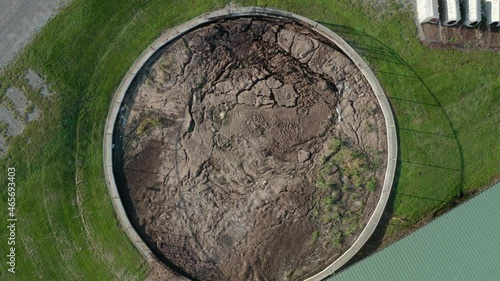 Rising aerial of manure pit, slurry in round storage holding tank. Farm agriculture theme.