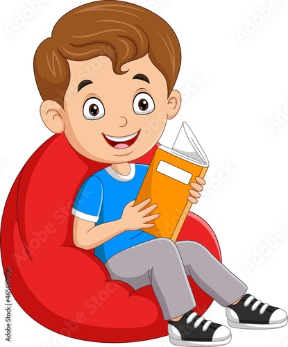 Little boy reading a book and sitting on big pillow