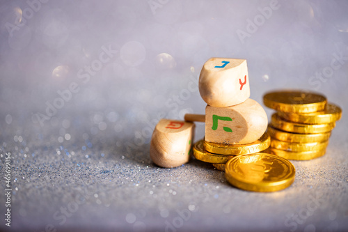 Hanukkah jewish holiday greeting card with wooden dreidels (spinning top) on silver background with glare  photo