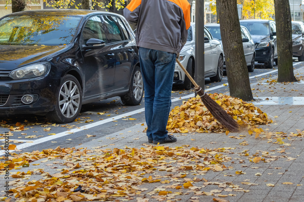 The worker sweeps the leaves into a pile The worker sweeps the leaves into a pile