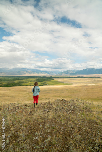 The girl in a picturesque place looks at the mountains and the steppe