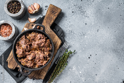 Canned stewed horse and beef meat in a pan. Gray background. Top view. Copy space
