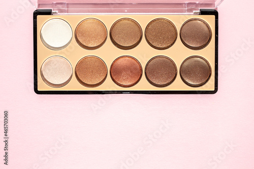 Makeup palette with beige sparkling eyeshadow on a powdery background. Flat lay, place for text.