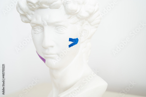 Gypsum statue of David head with kinesio tape. Face-taping  lifting treatment on face concept