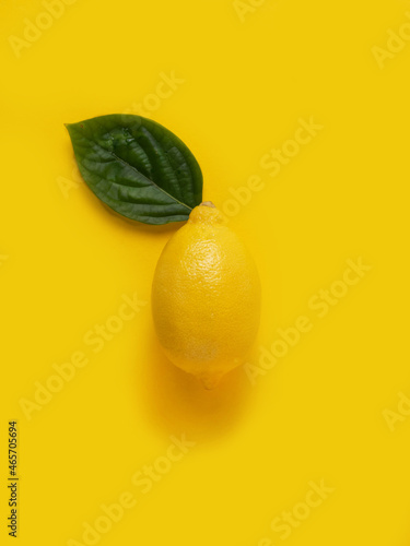 Lemon with a green leaf on a yellow background.