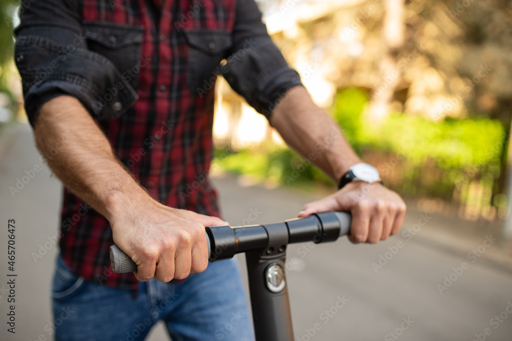 Close up of a man driving an electrical scooter on the street wearing a watch Close up of a man driving an electrical scooter on the street wearing a watch
