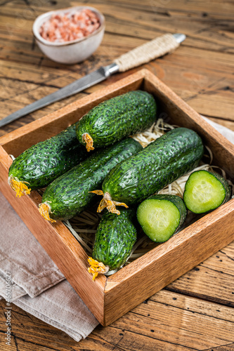 Fresh Green Cucumbers in a wooden box. Wooden background. Top view