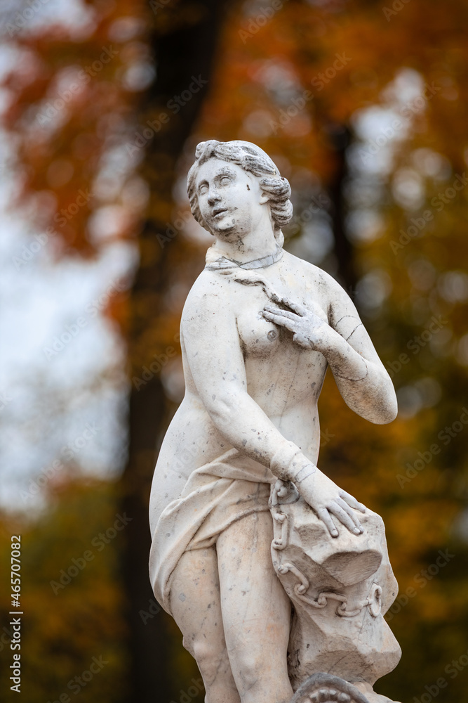 Old park statue of sensual Greek or Italian Renaissance Era woman with flowers in city park went to golden Autumn colors, Old park statue of sensual Greek or Italian Renaissance Era woman with flowers in city park went to golden Autumn colors,