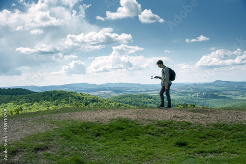Young man filming with mobile phone on a grip walking on trail 