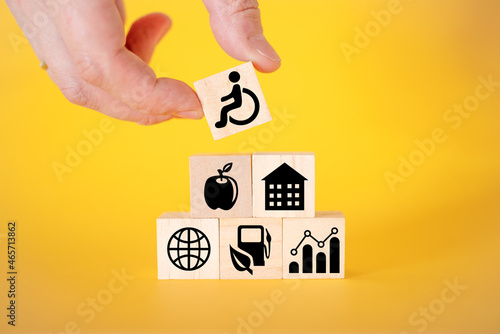 Icons for disabled people on wooden cubes, yellow background.