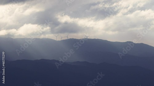 光芒の差す山並みと風力発電の風車