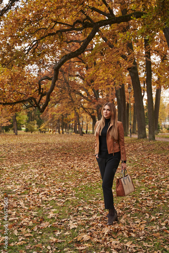 young beautiful woman stands in autumn park under yellow trees on yellow foliage © Elena