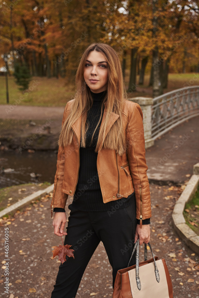young beautiful woman near a beautiful bridge walks in an autumn park among yellow trees