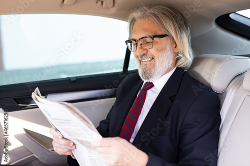 A handsome elderly businessman is in the car