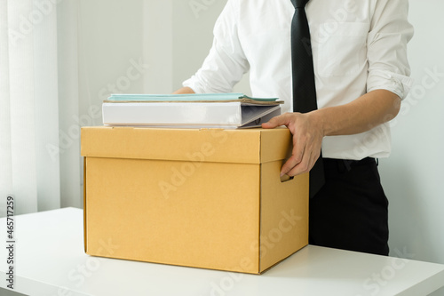 A male office worker is unhappy with being fired from a company packing things into cardboard boxes. The young man was stressed and disappointed by being fired. concept of layoffs and unemployment