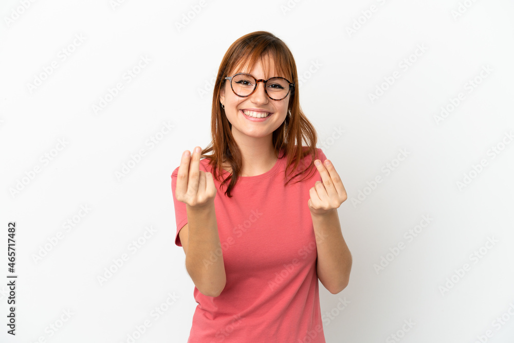 Redhead girl isolated on white background making money gesture Redhead girl isolated on white background making money gesture