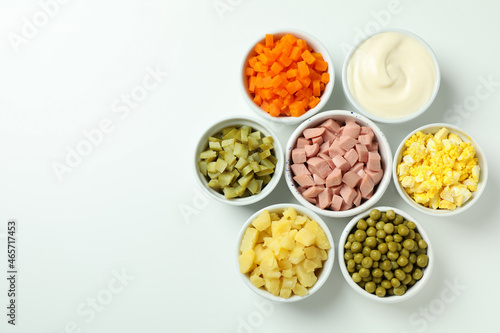 Bowls with Olivier salad ingredients on white background