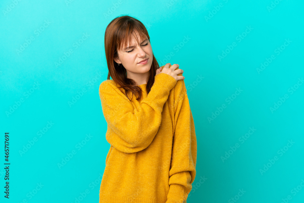 Redhead girl isolated on blue background suffering from pain in shoulder for having made an effort Redhead girl isolated on blue background suffering from pain in shoulder for having made an effort