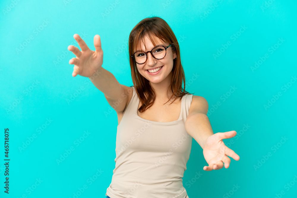 Redhead girl isolated on blue background presenting and inviting to come with hand Redhead girl isolated on blue background presenting and inviting to come with hand