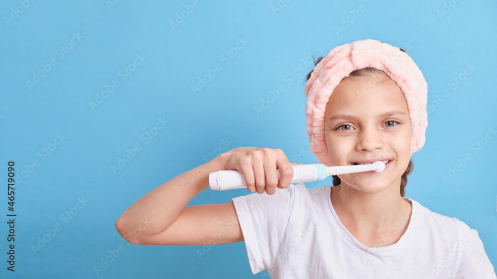 beautiful girl very brushes her teeth with an electric toothbrush on a blue background close-up beautiful girl very brushes her teeth with an electric toothbrush on a blue background close-up