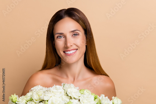 Portrait of attractive cheerful woman holding fresh white romantic bunch isolated on beige pastel color background