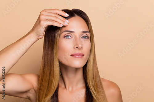 Portrait of attractive woman touching clear smooth silky flawless skin lifting solution effect isolated over beige pastel color background