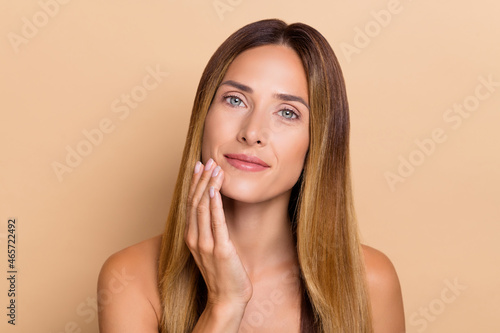 Portrait of attractive cute long-haired woman touching soft clean flawless pure skin lifting isolated over beige pastel color background