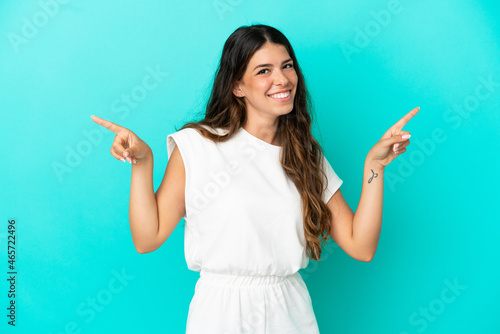 Young caucasian woman isolated on blue background pointing finger to the laterals and happy