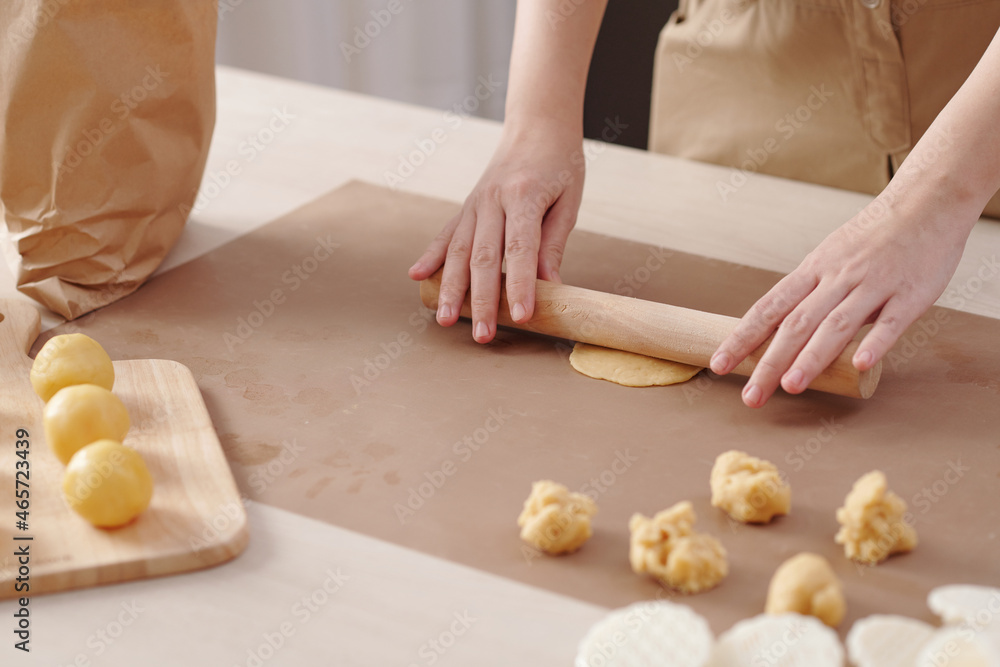 Close-up image of woman rolling out piece of dough when making mooncakes at home
