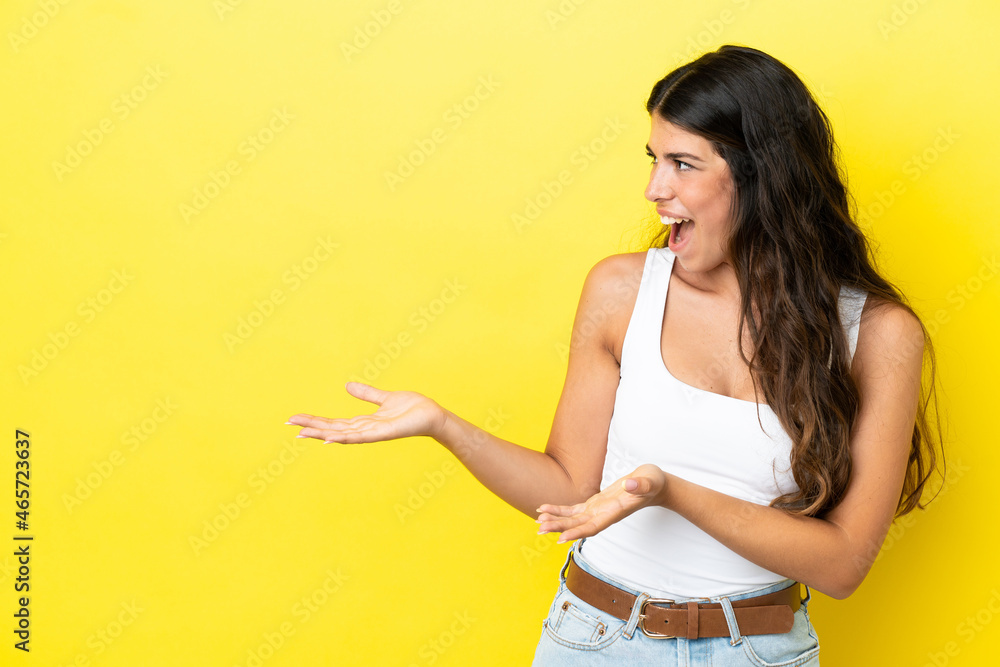 Young caucasian woman isolated on yellow background with surprise expression while looking side Young caucasian woman isolated on yellow background with surprise expression while looking side