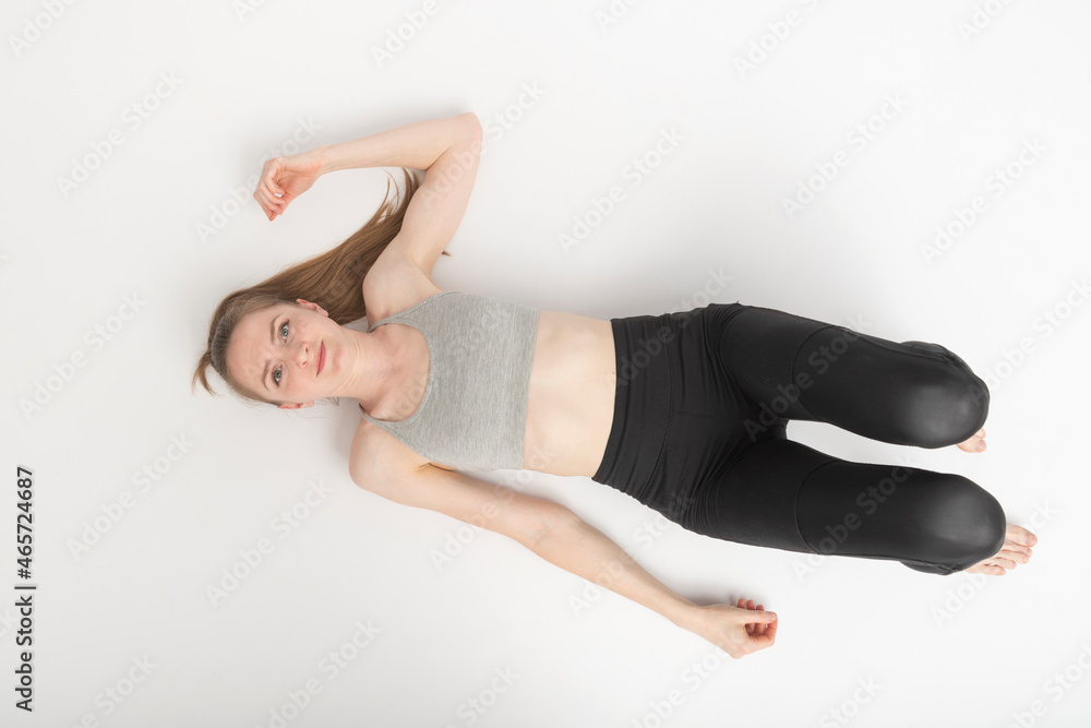 Teenage girl after sports workout rests on the white floor. Portrait on white background top view. Teenage girl after sports workout rests on the white floor. Portrait on white background top view.
